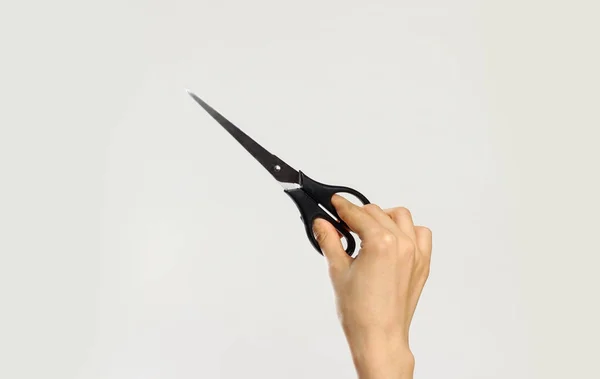 Female hands holding black scissors. Isolated on gray background — Stock Photo, Image