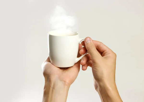 Mão masculina segurando caneca de vidro branco vazio. Isolado em cinza backgr — Fotografia de Stock