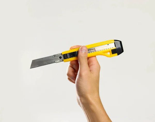 Mannelijke handen met gele scherpe box cutter. Geïsoleerd op grijze bac — Stockfoto