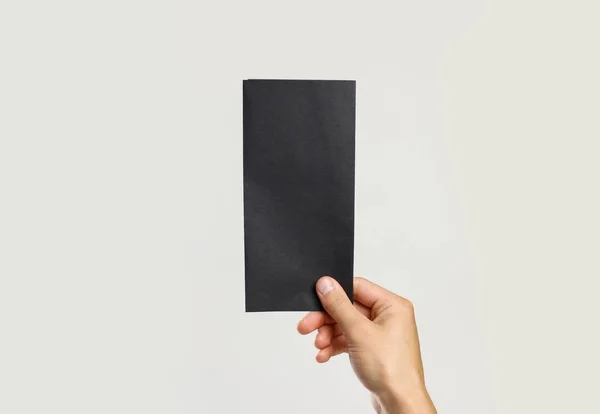 Мужские руки держат черный лист бумаги. Изолированный на серой спине — стоковое фото