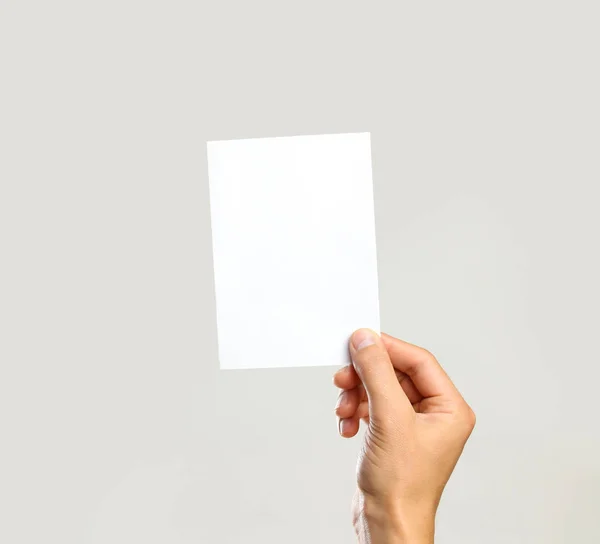 Mains masculines tenant une feuille blanche de papier. Isolé sur le dos gris — Photo
