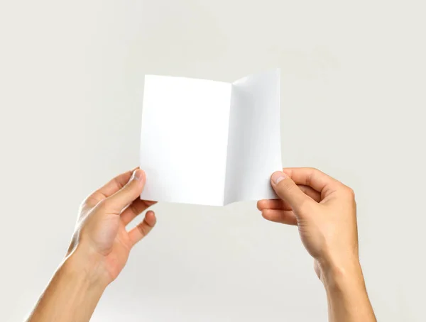 Αρσενικό χέρια κρατώντας ένα λευκό φύλλο χαρτί. Απομονωμένα σε γκρι πίσω — Φωτογραφία Αρχείου