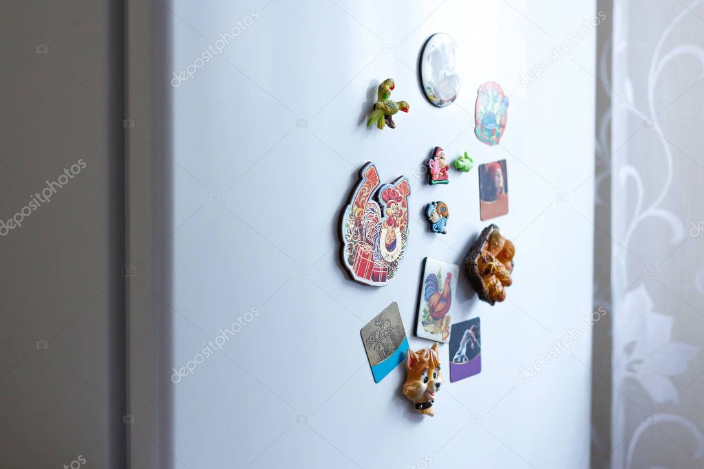 Different magnets on a white refrigerator in the kitchen. Closeu
