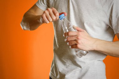 Adam bir şeffaf plastik su şişesi tutuyor. Açık şişe