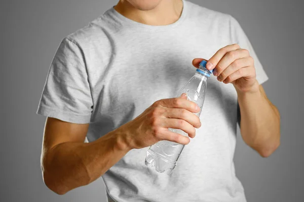 O cara está segurando uma garrafa de água de plástico transparente — Fotografia de Stock