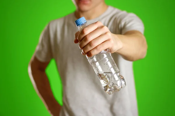 O cara está segurando uma garrafa de água de plástico transparente — Fotografia de Stock