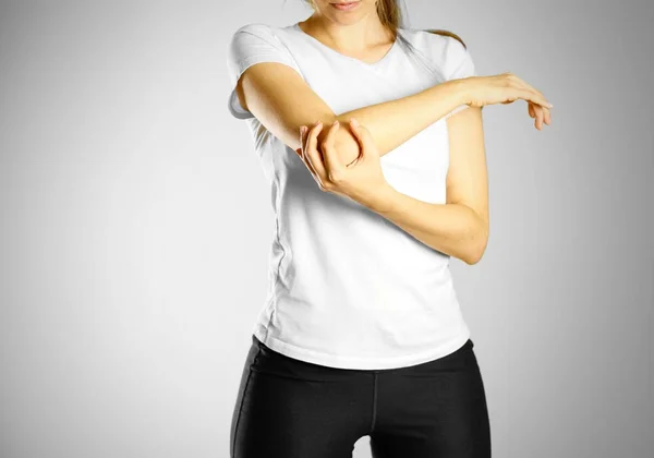 La ragazza dolente gomito. Il dolore al braccio. Isolato su grigio — Foto Stock