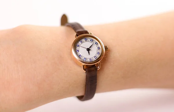 Женские золотые часы с кожаным ремешком на руке. На белом баке — стоковое фото