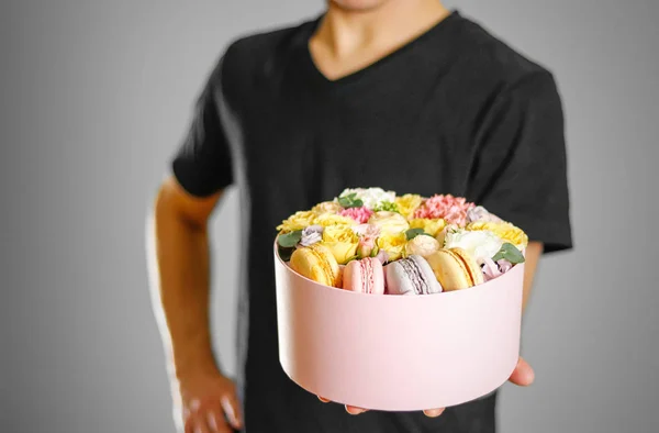 Человек с цветами и печеньем в коробке. Руки держат ракету i — стоковое фото