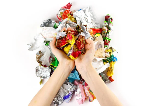 Hands holding a bunch of candy wrappers on a white background. C — Stock Photo, Image