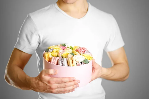 En mann med blomster og kaker i en eske. Hold rakett i. – stockfoto