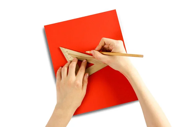 Hände, die ein dreieckiges Lineal und Bleistift auf rotem Papier halten. clos — Stockfoto