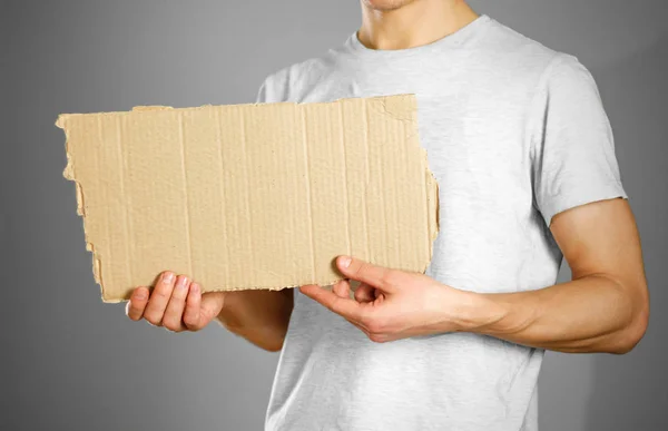 Ein junger Mann in weißem T-Shirt hält einen Karton in der Hand. vor — Stockfoto