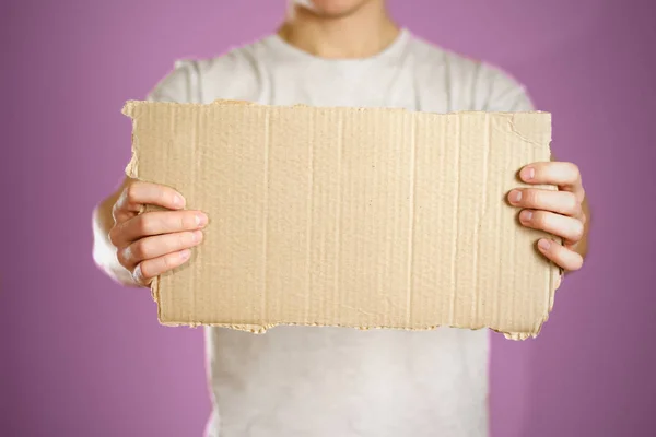 A young guy in a white t-shirt holding a piece of cardboard. Pre — Stock Photo, Image