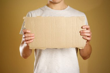 Beyaz bir t-shirt bir karton parçası tutan genç bir adam. Öncesi