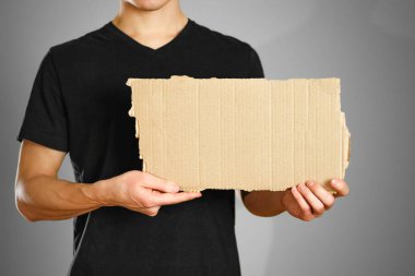 Siyah t-shirt bir karton parçası tutan genç bir adam. Öncesi