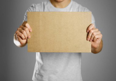 Beyaz bir t-shirt bir karton parçası tutan genç bir adam. Öncesi