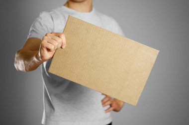 Beyaz bir t-shirt bir karton parçası tutan genç bir adam. Öncesi