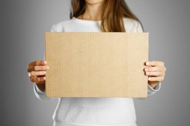 Beyaz ceketli bir karton parçası tutan genç bir kız. Öncesi