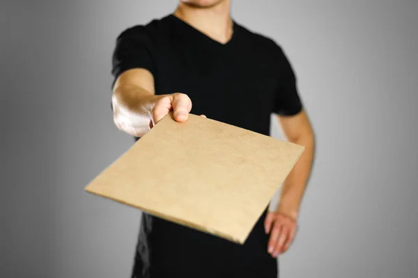 Молодой парень в черной футболке держит кусок картона. Пре — стоковое фото