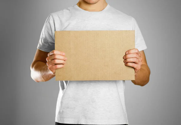 Un joven con una camiseta blanca sosteniendo un pedazo de cartón. Antes de —  Fotos de Stock