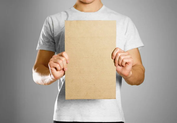 Молодой парень в белой футболке держит кусок картона. Пре — стоковое фото
