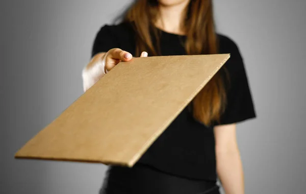 Ein junges Mädchen in einem schwarzen T-Shirt hält einen Karton in der Hand. pr — Stockfoto