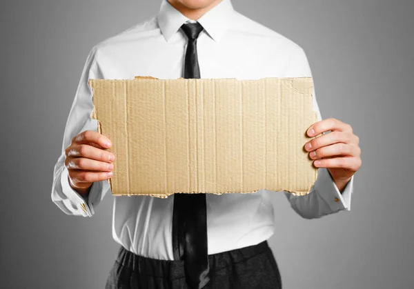 Empresário de camisa branca e gravata segurando um pedaço de papelão . — Fotografia de Stock