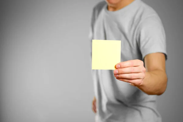 Un homme en t-shirt gris tient un bâton carré vide jaune propre — Photo