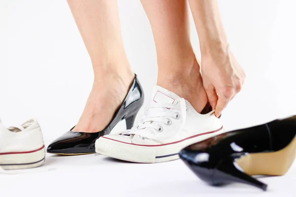 Dívka měnící se boty. Odstraní černé boty a nosí bílé tenisky — Stock fotografie