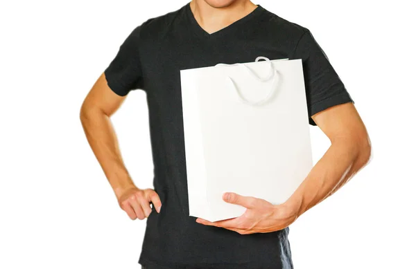 Ο τύπος κρατάει ένα λευκό δώρο τσάντα. Απομονωμένα σε λευκό backgroun — Φωτογραφία Αρχείου