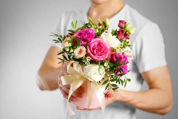 Man in white t shirt holding in hand rich gift bouquet. Composit