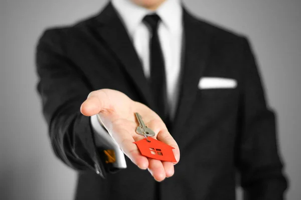 Muž v černém obleku drží klíče k domu. Přívěsek na klíče červené — Stock fotografie