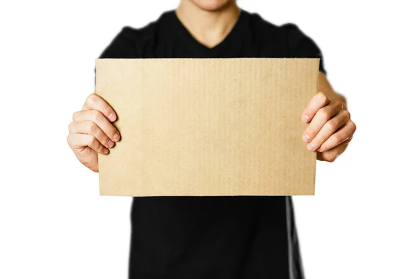 Um jovem com uma t-shirt preta segurando um pedaço de papelão. Pré — Fotografia de Stock