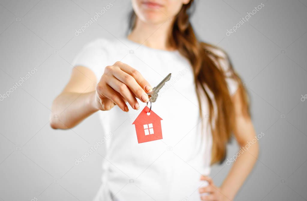 A girl holds the keys to the house. Key ring red house