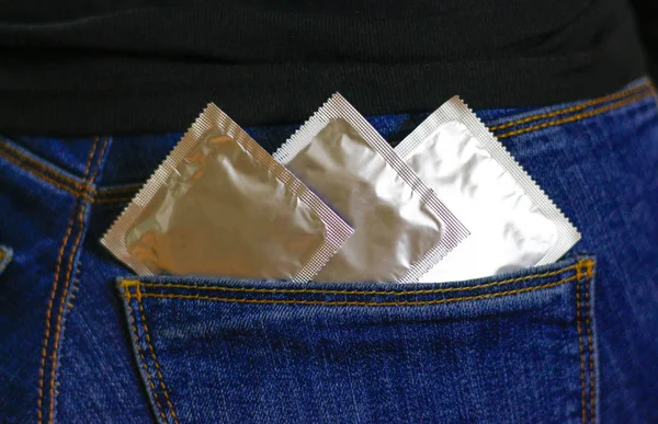 Três preservativos no bolso de calças de ganga azuis. Fechar — Fotografia de Stock