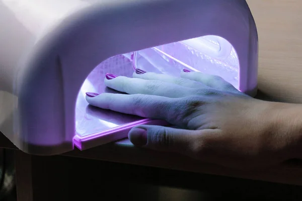 Chica seca gel esmalte aplicado a las uñas bajo un ultravioleta — Foto de Stock