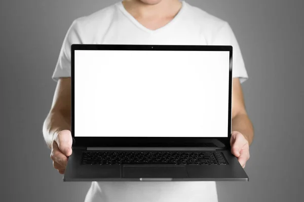 Beyaz tişörtlü bir adam dizüstü bilgisayar tutuyor. Kapatın. G 'de izole edilmiş — Stok fotoğraf