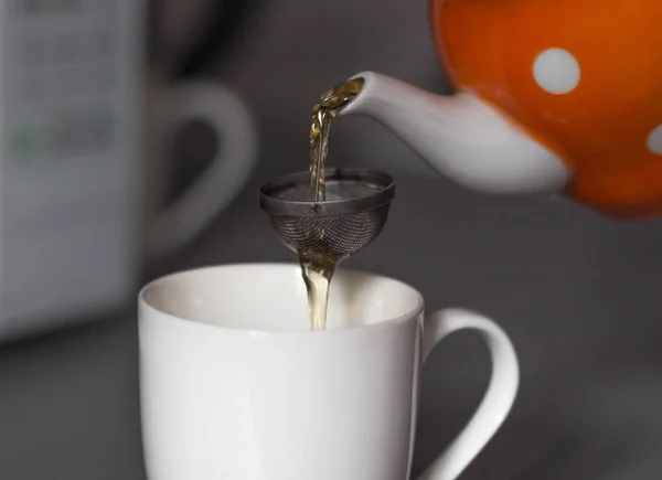 Versare il tè dalla teiera attraverso un setaccio. Tea party. Da vicino. — Foto Stock