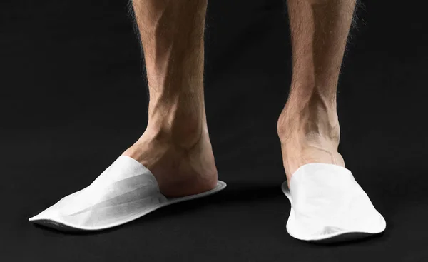 The feet of a man in white slippers. On black background. Close — Stockfoto