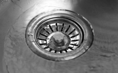 Su, metalik lavabonun ortasına akar. Kapat.