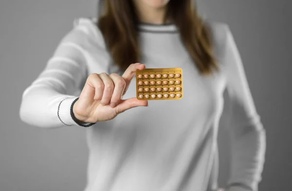 Girl holding birth control pills. Close up. Isolated on grey bac — Stock Photo, Image