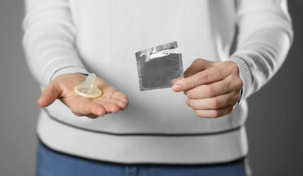 Prezervatif tutan bir kız. Kapatın. Gri arkaplanda izole — Stok fotoğraf