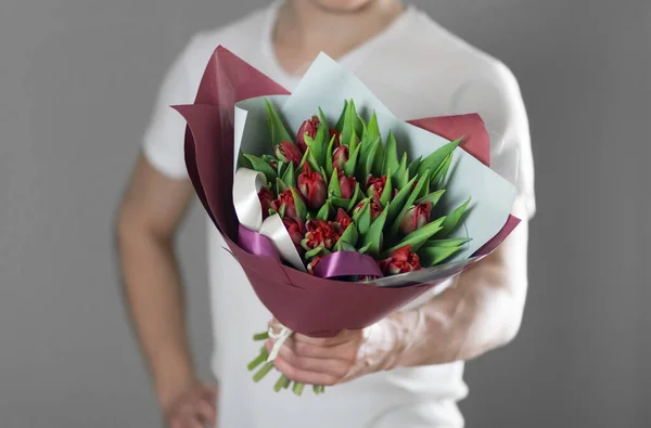 Mężczyzna trzyma piękny bukiet czerwonych tulipanów. Zamknij drzwi. Izolacja — Zdjęcie stockowe