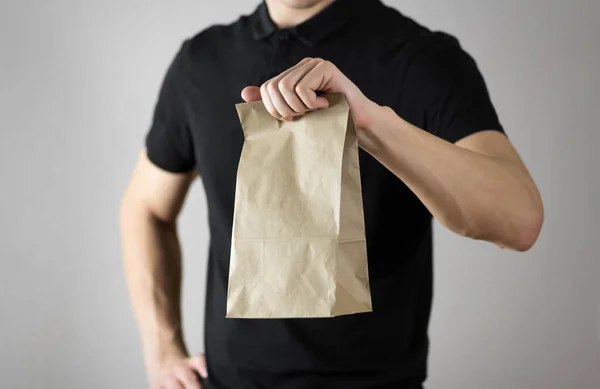 Hombre Sostiene Una Bolsa Papel Cerca Aislado Sobre Fondo Gris — Foto de Stock