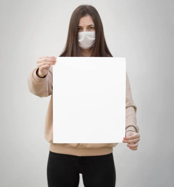 Ένα Κορίτσι Ιατρική Μάσκα Κρατάει Ένα Άδειο Λευκό Χαρτί Κλείσε — Φωτογραφία Αρχείου