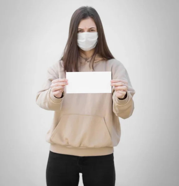 Ένα Κορίτσι Ιατρική Μάσκα Κρατάει Ένα Άδειο Λευκό Χαρτί Κλείσε — Φωτογραφία Αρχείου