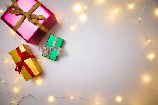 Chtistmas presents wrapped with ribbon and fairy lights on white background — Stock Photo, Image