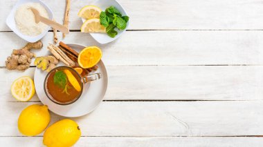 Kırsal beyaz masada zencefil, nane ve narenciye ile bitki çayı.