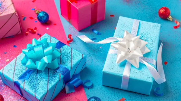 Presents wrapped in brightly colored blue pink and red paper with glitter ribbons and other decorations — Stock Photo, Image